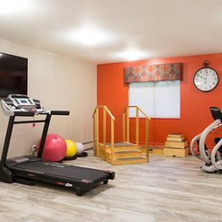 A modern gym space featuring various exercise equipment including a treadmill, exercise bike, and fitness accessories.