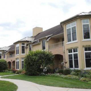 A suburban residential building with well-maintained landscaping and large windows.