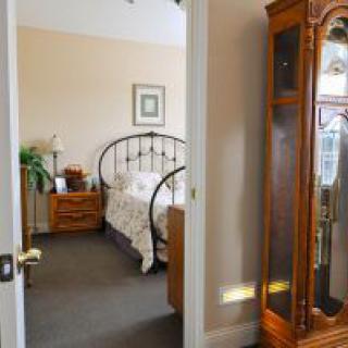 A cozy bedroom with a wrought iron bed, wooden nightstand, and a grandfather clock.