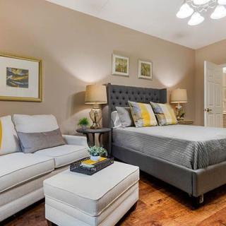 A cozy bedroom featuring a stylish bed with decorative pillows, a comfortable sofa, and elegant lighting.