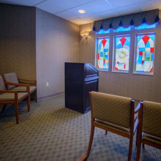 A serene chapel interior with stained glass windows and arranged seating.