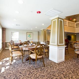 A well-lit dining area with stylish tables and chairs arranged on a patterned carpet.