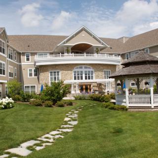 A large building with a well-maintained garden, featuring a stone pathway leading to a gazebo.