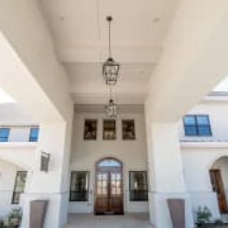 A grand entrance with tall ceilings, featuring elegant hanging lanterns and large windows.