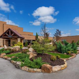 A beautifully landscaped entrance to a building with clear blue skies and scattered clouds.