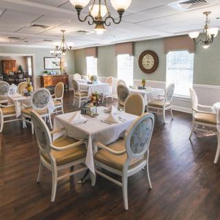 An elegant restaurant dining room with neatly arranged tables and chairs, decorated with chandeliers.