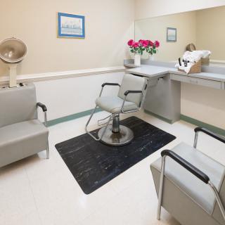 A cozy salon interior with chairs, a mirror, and floral decoration.