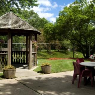 A tranquil garden setting with a gazebo and outdoor seating under a sunny sky.