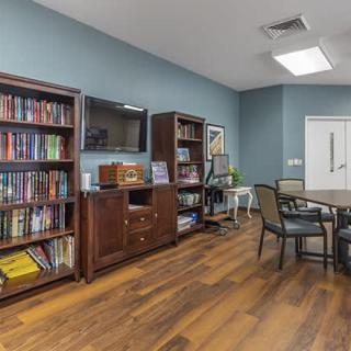 A cozy reading room with bookshelves, a table, and chairs on a wooden floor.