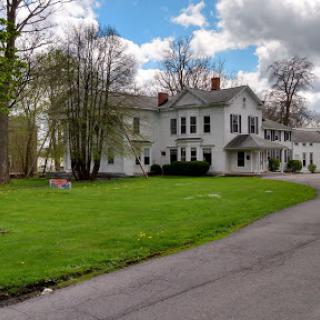 A charming white house surrounded by greenery and a blue sky.