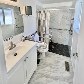 A modern and clean bathroom with marble flooring, featuring a sink, toilet, and shower area.