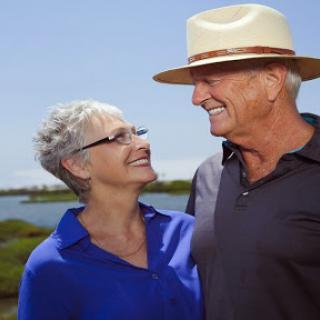 A joyful moment shared between an elderly couple, enjoying a sunny day by the water.