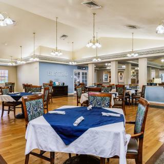 A well-lit dining room with tables and chairs neatly arranged.