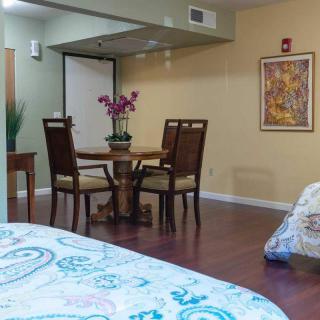 A cozy dining area with a round table and chairs, adorned with flowers, adjacent to a bed in a warmly decorated room.
