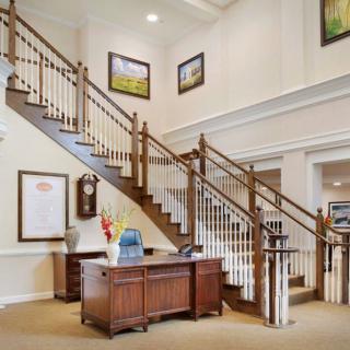 A welcoming interior featuring a grand staircase and a reception desk adorned with artwork.