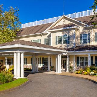 A sunny view of a large residential building with a driveway and entrance.