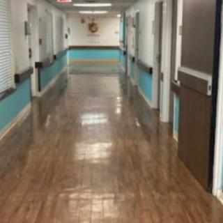 A clean and empty hospital corridor with closed doors along the sides.