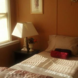 A cozy bedroom with a bed, lamp, and window.