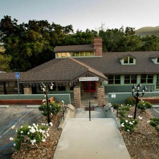 An elegant restaurant building with a landscaped pathway and flowers leading to the entrance.
