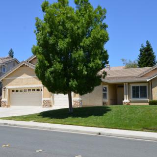 A suburban house with a garage and a front lawn on a sunny day.