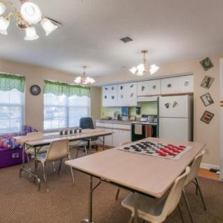 A classroom setup with tables, chairs, and a kitchen area.