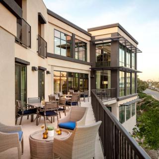 A modern building with a spacious balcony featuring stylish patio seating.