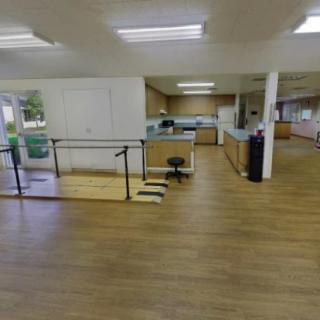 A spacious rehabilitation center with wooden flooring and exercise equipment.
