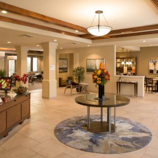 A modern and elegantly designed lobby area with stylish furniture, warm lighting, and decorative floral arrangements.
