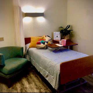 A cozy hospital room featuring a single bed, an armchair, and some decorative elements.