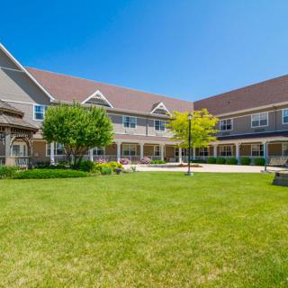 A large residential building with a well-maintained lawn and garden area under a clear blue sky.