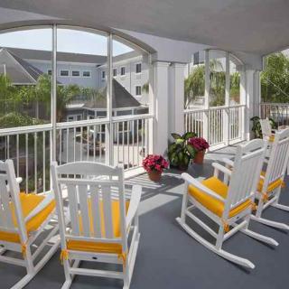 A sunny porch area with yellow-cushioned rocking chairs and potted plants.