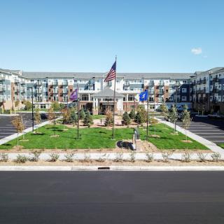 A modern residential complex featuring well-maintained landscaping and an American flag.