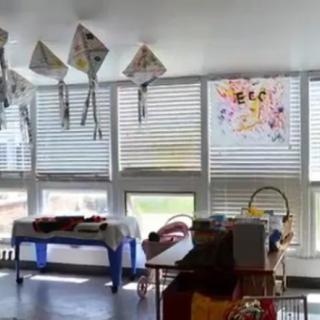 A brightly lit classroom with kites hanging from the ceiling and children's artwork on display.