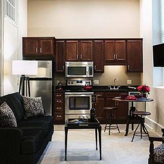 A modern apartment kitchen with dark cabinetry and stainless steel appliances.