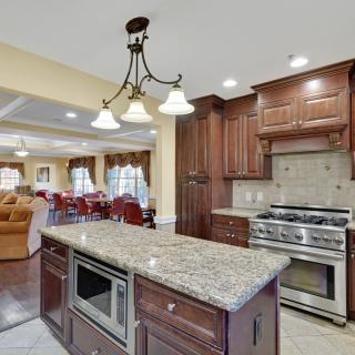 A modern kitchen featuring a central island with granite countertops, wood cabinetry, and a stainless steel stove.