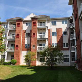 A residential apartment building with brick and white facade under a clear blue sky.