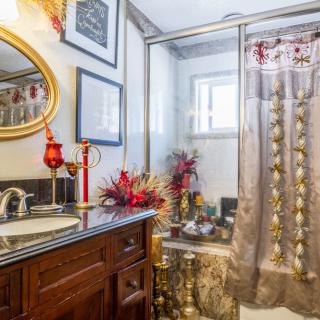 A well-decorated bathroom with a mirror, vanity, and shower area adorned with flowers.
