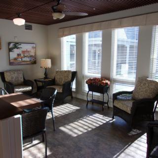 A cozy living room with ample natural light, featuring comfortable seating and large windows.