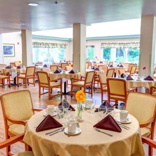 An elegant dining room with neatly arranged tables and chairs, set for a meal.