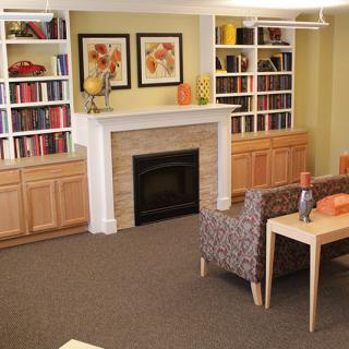A cozy living room with a fireplace, bookshelves, and comfortable seating.