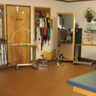 A physical therapy room equipped with various rehabilitation tools and a large mirror.