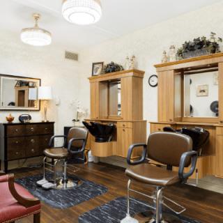 A well-organized hair salon interior with comfortable chairs and modern wooden styling stations.