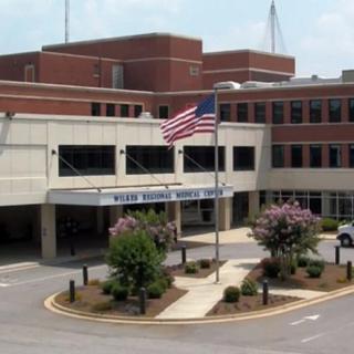 The image shows a hospital building with an American flag at the entrance.