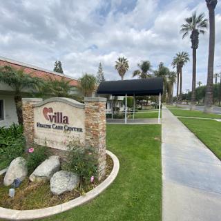 Entrance to Gilla Residential Care Center featuring well-maintained landscaping and palm trees.