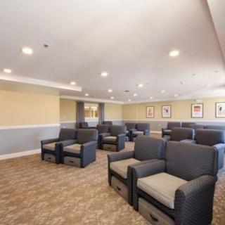A modern lounge area with multiple armchairs arranged in rows, featuring neutral tones and bright lighting.