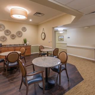 A cozy dining area with round tables, chairs, and decorative wall art.
