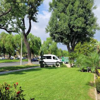 A serene park scene featuring lush green grass, trees, and a parked vehicle.