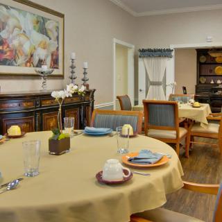 A cozy dining room with tables set for a meal, featuring elegant decor and warm lighting.