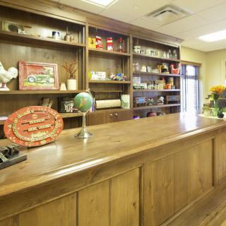 A reception area with a wooden desk and shelves filled with various decorations.