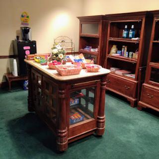 A cozy setup featuring a wooden display island filled with snacks and surrounded by shelves in a reception area.